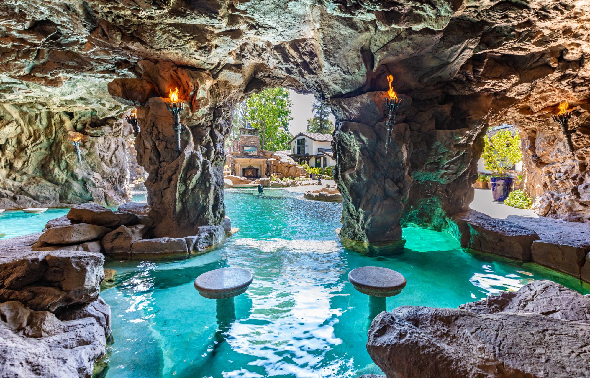 Grotto swim-up bar with tiki torches at Drake's estate