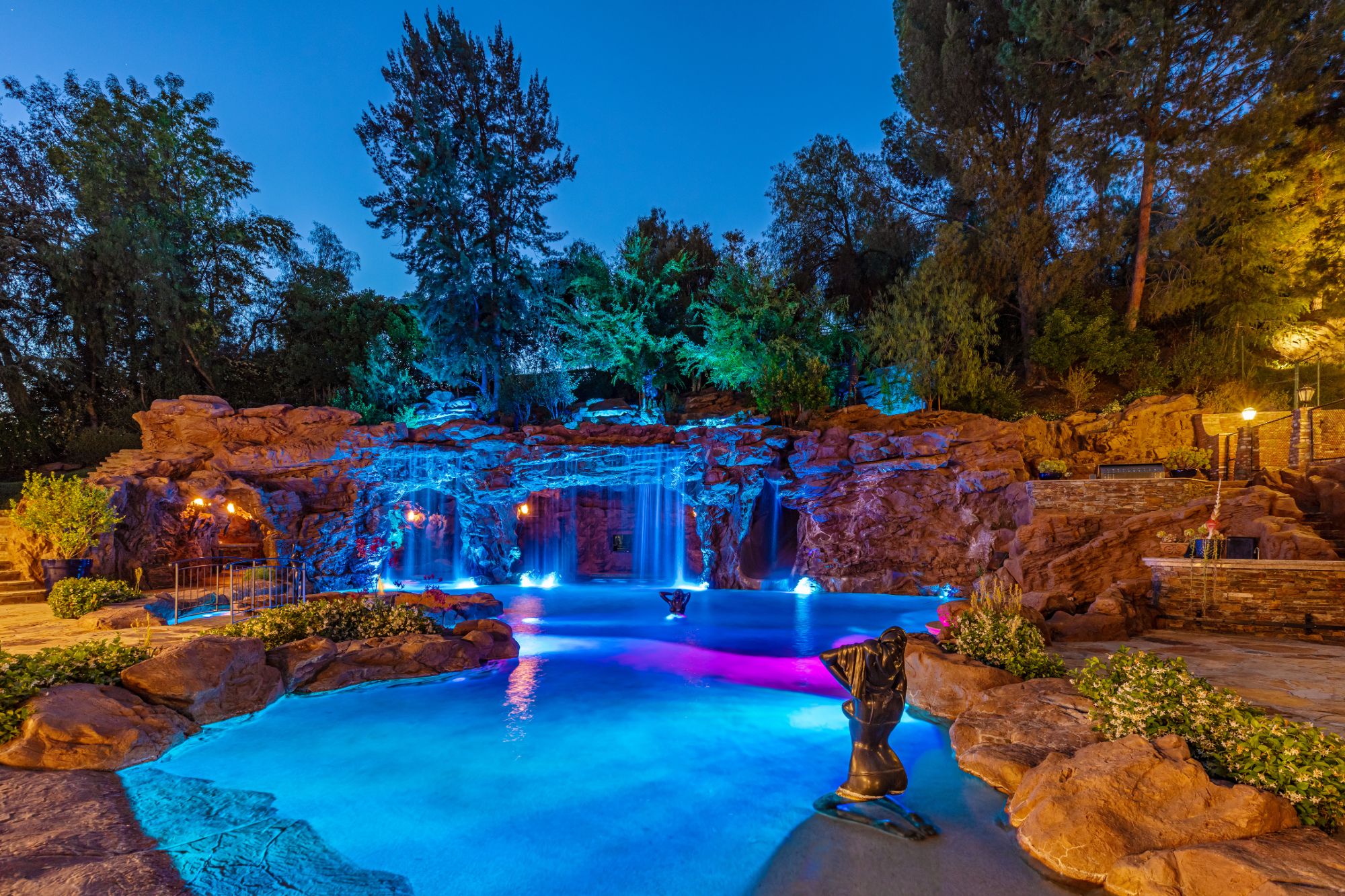 Night view of the lagoon pool and illuminated waterfalls at Drake's YOLO Estate